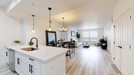 Located at 6851 S Gaylord St in Centennial, CO, this well-appointed 3-bedroom, 3-bathroom single-floor residence offers a thoughtfully designed open-concept layout. Light wood-tone flooring flows seamlessly throughout, connecting the kitchen, dining, and living areas into one cohesive, airy space. The modern kitchen is a standout feature, boasting white cabinetry, stainless steel appliances, a large white quartz waterfall island with bar seating, a matte black faucet, and stylish pendant lighting. The adjacent dining area centers around a rustic round table beneath an elegant chandelier, while a large mirror adds depth to the space. The living room is bright and welcoming, with a generous window dressed in vertical blinds that invite natural light. The primary bedroom is spacious and serene, offering natural light from dual windows. Additional bedrooms are comfortably sized with light-filled windows. All three bathrooms are finished in a clean, contemporary style featuring white soaking tub-shower combos, matte black fixtures, white vanities with quartz countertops, and open shelving. A utility room and hallway with closets round out this efficient and modern floor plan.