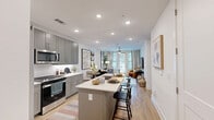 Located at 4115 Lake St in Alpharetta, GA, this thoughtfully designed one-bedroom, one-bathroom residence offers an efficient and functional layout across a single floor. The open-concept kitchen and living area serves as the heart of the home, featuring gray shaker-style cabinetry, white quartz countertops, a classic subway tile backsplash, and stainless steel appliances including a gas range and built-in microwave. A central island with bar seating provides additional prep space and casual dining. Light wood-tone flooring flows seamlessly throughout, enhancing the bright, airy atmosphere created by recessed lighting and large windows. The living area is generously sized, with access to a private balcony and abundant natural light streaming through floor-to-ceiling glass doors. The bedroom offers a comfortable retreat with multiple windows, a ceiling fan, and a dedicated closet. The bathroom features a wide vanity with gray cabinetry, white quartz countertop, and a large framed mirror with modern lighting. Additional conveniences include an in-unit laundry area and a utility room, making this residence as practical as it is stylish.