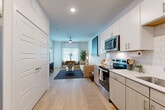This 1-bedroom, 1-bathroom residence in Austin, TX offers a clean, modern aesthetic throughout its efficiently laid-out single floor. Light wood-tone flooring runs seamlessly across all main areas, creating a cohesive and airy feel from entry to living space.

The kitchen is well-appointed with white upper cabinetry, warm wood-toned lower cabinets, white subway tile backsplash, light countertops, and a full suite of stainless steel appliances including a range, over-the-range microwave, dishwasher, and a side-by-side refrigerator with ice and water dispenser. Recessed lighting keeps the kitchen bright and functional.

The open layout flows naturally into the living area, which benefits from multiple windows dressed with blinds and sheer curtains, allowing ample natural light. A ceiling fan adds comfort, and a glass door provides direct outdoor access.

The bedroom is a comfortable retreat featuring a ceiling fan, large windows with natural light, and wood flooring. A dedicated closet provides practical storage.

The bathroom features a wood-toned vanity with ample drawer and cabinet storage, a white countertop, a large framed mirror, and light flooring that ties the space together. The overall design throughout is contemporary and consistent, emphasizing clean lines and neutral tones.