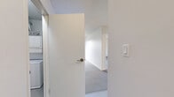 Located at 160 Pinehouse Dr in Saskatoon, Saskatchewan, this one-bedroom unit offers a straightforward and functional single-floor layout. The interior is finished with clean white walls and textured ceilings throughout, creating a bright and neutral atmosphere that is easy to personalize.

The generously sized bedroom is carpeted and features baseboard heating along the wall, ensuring comfort during colder months. A window allows natural light to filter in, while ample floor space provides flexibility for furniture arrangement. The room connects conveniently to the rest of the unit via a central hallway.

The main living area continues the carpeted flooring and is illuminated by a window that brings in natural light. A pendant light fixture is positioned overhead, and baseboard heaters line the perimeter, maintaining consistent warmth. The open feel of the living space transitions smoothly into the kitchen and adjoining areas, which feature light hard-surface flooring.

A dedicated laundry area houses a stacked Whirlpool washer and dryer unit, offering the convenience of in-suite laundry. The unit also includes a bathroom with a glass-enclosed shower. Throughout the space, white trim and clean lines contribute to a cohesive, understated aesthetic well-suited for comfortable everyday living.