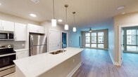 This 2-bedroom, 2-bathroom residence at The Wyatt in North Little Rock, Arkansas offers a well-designed, single-floor layout with contemporary finishes throughout. The open-concept kitchen and living area serves as the heart of the home, anchored by a large center island with a white quartz countertop, double undermount sink, and pendant lighting overhead. The kitchen is outfitted with white shaker-style cabinetry, a subway tile backsplash, and a full suite of stainless steel appliances, including a refrigerator, range, microwave, and dishwasher. Wood-style plank flooring extends seamlessly from the kitchen into the spacious living area, which features a ceiling fan and large windows that invite generous natural light. Both bedrooms are comfortably sized, each with ceiling fans and large windows fitted with blinds. The two bathrooms maintain a clean, neutral palette with white vanity cabinetry, quartz countertops, and light wood-style flooring. One bathroom includes a soaking tub with white subway tile surround, while the other features a walk-in shower. Each bathroom offers access to a dedicated closet, adding practical storage throughout the residence.