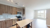 Located at 2803 Poag St in Alexandria, Virginia, this single-floor, 2-bedroom, 2-bathroom residence offers a thoughtfully designed layout with clean, contemporary finishes throughout. The open kitchen is a standout feature, equipped with stainless steel appliances including a refrigerator, range, microwave, and dishwasher, complemented by wood-toned cabinetry, white quartz countertops, a subway tile backsplash, and light hardwood-style flooring. The adjacent living area flows seamlessly from the kitchen, creating a cohesive and functional common space. Both bedrooms are carpeted and filled with natural light courtesy of large windows with outdoor views of surrounding greenery and the neighborhood. The primary bedroom is generously sized and includes ample closet space with double doors. The two bathrooms are finished with neutral tile flooring and wood-toned vanities with white countertops. One bathroom features a tub-shower combination with classic white subway tile surround, while the other offers a streamlined vanity and toilet setup. Soft, neutral tones are used throughout the residence, creating a calm and cohesive ambiance. A dedicated closet provides additional storage, rounding out this practical and modern Alexandria home.