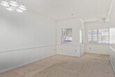 This well-organized one-bedroom, one-bathroom unit is laid out across a single floor, offering a comfortable and efficient use of space. The galley-style kitchen features dark wood cabinetry lining both walls, white countertops, a stainless steel double sink, a stainless steel refrigerator, and an electric range, all set over durable hardwood-style flooring. Adjacent to the kitchen, a hallway connects the main living areas and includes space for an in-unit washer, adding everyday convenience.

The living area is carpeted and bright, with neutral white walls and a ceiling fan with a light fixture overhead. A standout feature is the set of French doors that open to an outdoor area, allowing natural light to fill the room and providing a seamless connection to the exterior. The bedroom is generously proportioned, also carpeted, and equipped with its own ceiling fan. It connects directly to the rest of the unit through a private door and offers a dedicated closet for storage.

The bathroom is clean and functional, featuring a full tub-and-shower combination with white tile surround, a chrome shower rod, and a vanity sink. Two hallways guide circulation throughout the unit, contributing to a logical and easy-to-navigate floor plan. Overall, the space presents a practical and comfortable living environment.