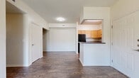 This well-appointed single-story home offers four bedrooms and two full bathrooms across a thoughtfully designed floor plan. The living area is bright and welcoming, featuring rich wood-style flooring, a ceiling fan, and sliding glass doors that invite natural light and provide direct access to the outdoors. Adjacent to the living space, the kitchen is accessible via a convenient bar-top pass-through and is equipped with warm honey-toned cabinetry, dark countertops, black appliances including a range and dishwasher, and a window above the sink for added light. A central hallway connects the living areas to the four bedrooms, each carpeted for comfort. The bedrooms feature closets with wire shelving, and the primary bedroom includes a spacious walk-in closet with multi-level wire rack storage. Two full bathrooms serve the home, each finished with wood-style flooring, warm wood vanities topped with dark granite-style countertops, and a tub-shower combination. The home also includes two closets for additional storage. With a clean, neutral color palette of crisp whites and soft beiges throughout, this home presents a move-in ready canvas well-suited for a variety of living arrangements.