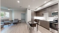 Located at 5420 55th St in San Diego, CA, this efficiently designed 2-bedroom, 2-bathroom residence offers a modern, clean aesthetic across a single floor. The open-concept living area combines the kitchen, dining, and living room into one cohesive space, featuring light wood-style flooring, recessed lighting, and a neutral color palette. The kitchen is outfitted with dark wood cabinetry, white countertops, stainless steel appliances including a full-size refrigerator, and ample upper and lower cabinet storage. The living area benefits from a ceiling fan and a window offering views of surrounding greenery, lending the space a bright and airy feel. Both bedrooms are carpeted and include dedicated closets with built-in shelving and hanging rods for organized storage. Each bedroom features a window that allows natural light and outdoor views of the landscaped surroundings. The two full bathrooms are finished with light wood-style flooring, white tiled shower-tub combos, and clean, minimal fixtures. An entrance area provides a practical transition into the home, complete with a louvered closet door. The overall design emphasizes functionality and modern simplicity throughout.