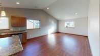 Located at 701 Trevino Trail in Mankato, Minnesota, this single-floor home offers a practical and comfortable layout with quality finishes throughout. The open-concept living and kitchen area is a standout feature, anchored by rich hardwood flooring and soaring vaulted ceilings fitted with recessed lighting. Multiple windows allow natural light to fill the space, creating a bright and welcoming atmosphere. The kitchen is well-appointed with warm oak cabinetry, granite-look countertops, stainless steel appliances including a refrigerator and range, a built-in peninsula for additional workspace, pendant lighting, and a double-basin sink. The living area flows seamlessly from the kitchen, offering generous open space ideal for a variety of furniture arrangements. The bedrooms are carpeted for comfort and each features a window with neighborhood views, providing natural light and ventilation. The full bathroom includes hardwood flooring, a full soaking tub and shower combo, a wood-trimmed vanity with a white countertop, and a well-lit mirror. A dedicated laundry room with tile flooring and shelving provides convenient in-unit utility. Consistent wood trim and neutral wall tones tie the home together with a cohesive, clean aesthetic throughout.