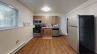 Located at 28 Yorkshire Terrace in Shrewsbury, Massachusetts, this single-floor unit offers a practical and well-organized layout. The kitchen is equipped with stainless steel appliances, including an electric range, over-the-range microwave, dishwasher, and refrigerator. Warm-toned wood cabinetry paired with granite-style countertops and wood-look laminate flooring give the kitchen a clean, functional aesthetic with ample upper and lower cabinet storage.

The living area features neutral carpet flooring, a textured ceiling, and a wall-mounted air conditioning unit alongside baseboard heating, ensuring year-round comfort. Natural light filters in through a window, creating a bright and open atmosphere. The space connects directly to the kitchen and bedroom areas, facilitating a straightforward flow throughout the unit.

The bedroom is generously sized, featuring the same neutral carpet and textured ceiling. It includes access to a spacious walk-in closet outfitted with wire shelving on three sides, offering considerable storage capacity.

The full bathroom is finished with wood-look flooring and includes a white vanity with under-sink storage, a wall-mounted mirror with overhead lighting, and a tub-shower combination with tile surround. The overall design of the unit is clean, neutral, and move-in ready.