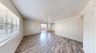 Located at 1327 Tennis Dr in Bedford, TX, this single-story 2-bedroom, 3-bathroom home offers a practical and well-organized layout. Wood-look laminate flooring runs consistently throughout, lending a cohesive, modern aesthetic to each room. The living room is bright and open, benefiting from a large window and a sliding glass door that invites natural light and connects the interior to the outdoors. A textured popcorn ceiling adds character to the main living areas. The kitchen is a functional highlight, featuring white cabinetry with matte black hardware, marble-style countertops, a tile backsplash, and black appliances including a range, over-the-range microwave, and refrigerator. A dedicated dining area adjoins the kitchen for convenient daily living. Both bedrooms are comfortably sized, each equipped with ceiling fans and natural light from windows. The primary bedroom offers a generous footprint, and a nearby closet provides dedicated storage. The hallway connects the rooms efficiently throughout the home. Three bathrooms include tub-shower combinations with white subway tile surrounds and wood-look tile flooring. The clean, neutral palette throughout the home creates a bright and welcoming atmosphere well-suited for comfortable everyday living.
