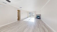 Located in Newport Beach, CA, this single-story, 2-bedroom, 2-bathroom home offers a thoughtfully designed layout with modern updates throughout. The open living room is a standout space, featuring light wood-look flooring, crown molding, a sleek tile-surround fireplace, and a ceiling fan. Large sliding glass doors flood the room with natural light and open directly to the patio, offering seamless indoor-outdoor living. The adjacent kitchen has been updated with crisp white shaker cabinetry, quartz countertops, a gray tile backsplash, stainless steel appliances, and a deep undermount sink. Both bedrooms are carpeted and comfortable, each equipped with a ceiling fan and natural light from windows with blinds. The generously sized primary bedroom provides ample space and closet storage. The two bathrooms are finished in a clean, modern style — one featuring a soaking tub with large-format white tile surround, and the other with a white quartz vanity, shaker cabinetry, and brushed nickel fixtures. Additional conveniences include in-unit laundry, pantry storage, and an entrance that leads into the welcoming living area. The outdoor patio extends to a lawn area, offering a private retreat in a desirable Newport Beach location.