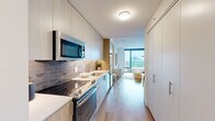 Located at 350 N Canal St in Chicago's vibrant West Loop neighborhood, this modern studio offers a thoughtfully designed open-concept layout that maximizes every square foot. Light hardwood flooring runs throughout, lending warmth and continuity to the space.

The galley-style kitchen is outfitted with contemporary two-tone cabinetry, quartz countertops, a patterned tile backsplash, and a full suite of stainless steel appliances, including a range, microwave, and dishwasher. The kitchen flows seamlessly into the combined living and sleeping area, where floor-to-ceiling windows flood the space with abundant natural light and frame sweeping views of the Chicago skyline.

The open living area comfortably accommodates both a sleeping arrangement and a dedicated living space, with room for a dining table. The clean white walls and bright, airy atmosphere create a calm, contemporary ambiance throughout.

The bathroom features a warm wood-toned vanity with a white quartz countertop, a large mirror, and a glass-enclosed walk-in shower finished with large-format tile, lending a refined, spa-like quality. The neutral color palette and modern fixtures tie the space together cohesively.

This studio combines efficient, modern design with an enviable Chicago location, offering both style and function in a compact yet well-appointed layout.