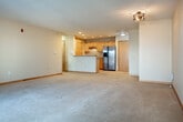 This single-floor residence offers a thoughtfully arranged layout with a clean, neutral aesthetic carried consistently through each space. The open living area is carpeted in light beige and benefits from generous natural light streaming through a sliding glass door that opens onto a private balcony, providing outdoor views. Warm wood-trimmed doors and light-toned baseboards add visual continuity throughout.

The kitchen is efficiently designed with light maple cabinetry, tile flooring, stainless steel appliances including a range and a side-by-side refrigerator with an ice dispenser, and a countertop with an integrated sink. A dedicated pantry with built-in shelving provides ample storage.

The bedrooms are carpeted and well-proportioned. One features a sliding glass door to the balcony, a walk-in closet, and additional door access, while another includes a standard window and generous floor space. A third carpeted room with ceiling light fixture offers flexible use. Closet space is present, with at least one bedroom featuring a full-width closet with a built-in hanging rod.

The bathroom is finished with tile flooring, a light maple vanity with an integrated sink, a wall mirror, and a tub-shower combination with a handheld showerhead. The overall ambiance is clean, functional, and move-in ready.