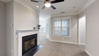 Located at 513 Cranbrook Dr in Asheville, NC, this single-story, 3-bedroom, 2-bathroom home offers a well-organized layout across a compact yet efficiently designed floor plan. The living and dining area serves as the heart of the home, highlighted by a classic fireplace with a white surround and black glass doors, crown molding, a ceiling fan with light fixture, and plush carpeting. Multiple windows dressed with white blinds allow natural light to fill the space.

The galley-style kitchen is well-appointed with white cabinetry, dark granite countertops, wood-look flooring, stainless steel appliances including a gas range and refrigerator, and a black fixture sink. A hallway from the kitchen leads directly to the laundry room, which houses a full-size washer and dryer with overhead wire shelving.

Each of the three bedrooms features carpeted flooring, a ceiling fan, and windows providing natural light. The primary bedroom offers a notably generous footprint among the three. Both bathrooms include granite-topped vanities, white cabinetry, and wood-look flooring, with one bath featuring a shower-tub combination. The overall aesthetic is neutral and move-in ready throughout.