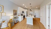 Located at 2250 Hawkins St in Charlotte's vibrant South End neighborhood, this single-floor residence offers a well-designed open layout that seamlessly connects the kitchen, dining, and living areas. The kitchen is a standout feature, showcasing white shaker cabinetry, a white subway tile backsplash, stainless steel appliances, and a central island with a matte black sink and pendant lighting overhead — all set atop warm hardwood-style flooring that flows throughout the main living spaces. The living area is bright and welcoming, featuring large windows and a glass door that flood the space with natural light and provide views of the surrounding community. The bedroom is a serene retreat, distinguished by a bold green accent wall, a ceiling fan, and a window with outdoor views. Its adjoining bathroom is cleanly finished with white cabinetry, a large wood-framed mirror, and tile flooring, leading directly into a spacious walk-in closet with built-in shelving. Throughout the residence, neutral wall tones, recessed lighting, and thoughtful design details contribute to a cohesive, contemporary aesthetic that balances comfort with modern style.
