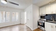 Located at 818 S Mariposa Ave in the heart of Los Angeles, CA, this efficiently designed studio unit offers a well-organized single-floor layout that maximizes every square foot. The open-plan kitchen and living area serve as the heart of the space, featuring light wood-tone flooring that flows seamlessly throughout. The kitchen is outfitted with crisp white shaker cabinetry, dark subway tile backsplash, dark countertops, stainless steel appliances including a gas range and refrigerator, and track lighting overhead — delivering a clean, modern aesthetic. The living area benefits from natural light through horizontal-blind-fitted windows and is topped with a ceiling fan with integrated lighting, adding both comfort and brightness. Two closets provide practical storage solutions, one featuring sliding doors. A wall-mounted heating unit near the entry ensures climate control year-round. The bathroom maintains the same clean, white palette with wood-look flooring, a window for natural light, and chrome fixtures. Crisp white walls and textured ceilings tie the entire unit together, creating a cohesive, move-in-ready space ideal for those seeking streamlined urban living in Los Angeles.