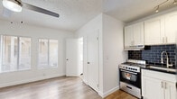 Located at 818 S Mariposa Ave in the heart of Los Angeles, CA, this efficiently designed studio unit offers a well-organized single-floor layout that maximizes every square foot. The open-plan kitchen and living area serve as the heart of the space, featuring light wood-tone flooring that flows seamlessly throughout. The kitchen is outfitted with crisp white shaker cabinetry, dark subway tile backsplash, dark countertops, stainless steel appliances including a gas range and refrigerator, and track lighting overhead — delivering a clean, modern aesthetic. The living area benefits from natural light through horizontal-blind-fitted windows and is topped with a ceiling fan with integrated lighting, adding both comfort and brightness. Two closets provide practical storage solutions, one featuring sliding doors. A wall-mounted heating unit near the entry ensures climate control year-round. The bathroom maintains the same clean, white palette with wood-look flooring, a window for natural light, and chrome fixtures. Crisp white walls and textured ceilings tie the entire unit together, creating a cohesive, move-in-ready space ideal for those seeking streamlined urban living in Los Angeles.