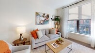 Located at 125 Clifford St in the heart of Providence, Rhode Island, this single-floor residence offers a well-designed layout with modern finishes and an urban aesthetic. The open-concept kitchen is a standout feature, equipped with sleek matte gray cabinetry extending to the ceiling, stainless steel appliances including a refrigerator, microwave, range, and dishwasher, and crisp white countertops complemented by a subway tile backsplash. A white kitchen island with seating provides additional prep space and casual dining. Light wood-tone flooring flows throughout the main living areas, adding warmth to the contemporary design. The living area is bright and welcoming, featuring large windows that frame views of the surrounding Providence streetscape and fill the space with natural light. The bedroom offers a serene retreat with oversized windows, neutral carpeting, and ample room for furnishings. A second bedroom or flex space also benefits from large windows with city views. The bathroom is finished with large-format tile flooring, a charcoal vanity with stone countertops, a wide mirror, and a glass-enclosed walk-in shower. Recessed lighting throughout ensures a clean, modern look. This residence combines functional urban living with refined design details in a prime Providence location.