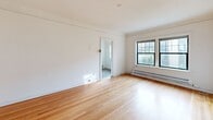 Located at 309 E Harrison St in Seattle's vibrant Capitol Hill neighborhood, this two-bedroom, one-bathroom unit offers a compact yet functional layout spread across a single floor. Warm-toned hardwood flooring runs throughout the living areas and bedrooms, lending a cohesive and inviting feel to the space.

The spacious primary bedroom is generously sized, featuring a large window that draws in natural light and a baseboard heating system. A charming arched doorway with decorative trim adds a touch of classic character. The second bedroom is similarly bright and well-proportioned, also equipped with baseboard heat. Both bedrooms benefit from dedicated closet spaces, providing practical storage solutions.

The kitchen retains a vintage aesthetic with white tile countertops accented by bold red trim, a wall-mounted chrome faucet, and white cabinetry — a nod to the building's historic charm. The bathroom offers a full tub-and-shower combination framed by elegant marble-look surround panels, a pedestal sink, and classic hexagonal floor tile.

A connecting hallway ties the rooms together efficiently. The overall palette of white walls and natural wood floors creates a clean, bright ambiance throughout. Baseboard heating is present in multiple rooms, ensuring comfort year-round in Seattle's temperate climate.