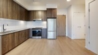 Located at 1915 Sooke Rd in Colwood, BC, this thoughtfully designed 2-bedroom, 2-bathroom unit offers a clean, contemporary aesthetic throughout. Light-toned laminate flooring flows seamlessly across the open-concept living, dining, and kitchen area, creating a bright and cohesive space. Large windows invite abundant natural light and frame green, tree-lined views, enhancing the airy atmosphere.

The modern kitchen is outfitted with dark wood-grain cabinetry that extends to the ceiling for generous storage, paired with stone countertops, a classic white subway tile backsplash, and a full suite of stainless steel appliances including a refrigerator, range, and dishwasher. The living area connects directly to a private balcony through a sliding glass door, offering serene outdoor views.

Both bedrooms are well-sized with large windows, light flooring, and sliding double-door closets. The primary bedroom features balcony access through a full-height glass door. The two bathrooms are finished with large-format tile flooring, stone-topped wood vanities, and glass-enclosed showers. Additional highlights include a versatile den, in-unit laundry, and three closets providing ample storage throughout.