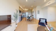 Unit 404 at 806 N Edinburgh Ave is a thoughtfully designed 960-square-foot apartment on the fourth floor in Los Angeles' desirable West Hollywood area. The open-concept layout connects the living, dining, and kitchen areas seamlessly, all finished with light hardwood flooring that runs throughout the unit. The modern kitchen features light wood cabinetry, stainless steel appliances including a full-size refrigerator and range, and a tile backsplash. The dining area accommodates a full table and chairs, ideal for everyday living and entertaining. The bright living room is anchored by floor-to-ceiling windows and a sliding glass door that opens to a private balcony offering open city views. Two well-proportioned bedrooms each feature large windows that invite abundant natural light and neighborhood views. The primary bedroom includes ample space for a dresser and seating area. A sleek, minimalist bathroom showcases large-format tile walls and flooring, a glass-enclosed walk-in shower with a built-in bench, a floating vanity with mirror, and modern fixtures. A clean, well-lit hallway with recessed lighting and matte black door hardware connects the rooms, reinforcing the unit's contemporary aesthetic throughout.