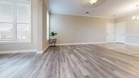 Located at 1430 Parapet Fort Drive in Duncan, SC, this thoughtfully designed 2-bedroom, 2-bathroom residence offers a clean, modern aesthetic across a single level. The open-concept living and dining area features elegant crown molding, warm neutral tones, and durable wood-look plank flooring that flows seamlessly throughout the main living spaces, creating a bright and airy atmosphere enhanced by multiple windows with white horizontal blinds.

The kitchen is a functional highlight, showcasing rich dark cabinetry, granite countertops, stainless steel appliances, and a peninsula with pendant lighting overhead — ideal for both cooking and casual dining. Large tile flooring anchors the kitchen area and transitions naturally into the adjoining hallways.

The spacious primary bedroom offers generous proportions, natural light from dual corner windows, and direct access to a walk-in closet equipped with wire shelving for organized storage. The second bedroom is equally well-lit and versatile. Both bathrooms feature tile flooring, dark wood vanities with granite countertops, and clean, neutral finishes.

Crown molding accents the living areas, while white baseboards and neutral wall tones lend a cohesive, polished look throughout. This residence combines practical layout efficiency with contemporary design details for comfortable everyday living.