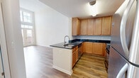 This contemporary 1000 square foot apartment in Herndon, VA, is a well-designed living space spread across two floors. The ground floor, spanning 650 square feet, hosts an open-concept kitchen and living room. The kitchen boasts wooden cabinetry, stainless steel appliances, and black granite countertops, creating a sleek and functional cooking area. Hardwood flooring extends throughout the main living spaces, adding warmth and elegance.

The upper floor, comprising 350 square feet, features a spacious 180 square foot bedroom with plush carpeting and large windows that flood the room with natural light. The bathroom showcases a modern vanity with ample storage and a large mirror. A closet provides additional storage space.

Notable features include high ceilings in the living area, complemented by tall windows and glass doors that lead to a balcony, enhancing the sense of space and light. The staircase connecting the two floors adds architectural interest to the interior. The neutral color palette throughout allows for versatile decorating options, while the overall design emphasizes a clean, minimalist aesthetic. This apartment efficiently utilizes its space, offering a comfortable and stylish urban living experience.