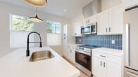 Located at 2017 West 44th Street in Cleveland, OH, this efficiently designed one-bedroom, one-bathroom unit offers a thoughtfully laid-out single floor of living space. The open-concept living and kitchen area is bright and airy, with light wood flooring underfoot and crisp white walls that enhance the sense of openness. A bank of windows in the living area frames views of mature trees, flooding the space with natural light.

The kitchen is a standout feature, boasting white shaker-style cabinetry with matte black hardware, a striking navy blue vertical tile backsplash, and a clean white countertop island with an undermount sink and a sleek black faucet. Stainless steel appliances, including a range, over-the-range microwave, and refrigerator, complete the modern kitchen setup. Statement pendant lights hang above the island, adding a contemporary touch.

The bedroom is carpeted for comfort and includes a double-door closet with built-in shelving and hanging rods, providing practical storage. The bathroom is finished with large-format grey tile flooring, a tub-shower combo with white tile surround, and matte black fixtures that tie the design together cohesively. The hallway connects the rooms efficiently, completing this well-appointed unit.