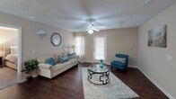 Located at 232 Willing Lakes Ct in Orangeburg, SC, this single-floor residence offers a thoughtfully designed layout with a warm, neutral color palette throughout. The living room serves as a welcoming central hub, featuring rich hardwood-style flooring, a ceiling fan with light fixture, and natural light streaming through windows with blinds and sheer curtains. The space is generous enough to comfortably accommodate a full seating arrangement.

The kitchen is designed for functionality, featuring warm wood cabinetry, light countertops, a breakfast bar peninsula, and a full suite of appliances including a refrigerator, electric range, and built-in microwave.

The home includes multiple bedrooms, each carpeted and equipped with ceiling fans. The primary bedroom is notably spacious, offering walk-in closet access and room for a king-sized bed with additional furnishings. A second bedroom also features a walk-in closet and is bright with natural light from a window. A third bedroom includes a dedicated closet and similarly comfortable proportions.

The bathrooms are clean and practical, each featuring a tub-shower combination, vanity with storage, and wood-toned cabinetry. Hardwood-style flooring extends into the bathroom areas, adding visual continuity throughout the home.