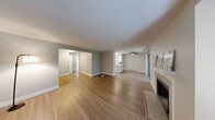 Located at 209 21st Ave SW in Puyallup, WA, this 2-bedroom, 2-bathroom residence offers a well-organized single-floor layout with a cohesive, neutral color palette throughout. The living room serves as the heart of the home, highlighted by a tile-surround fireplace with a white mantel and wood-style laminate flooring that extends into the adjacent hallway and kitchen areas. Natural light filters in through windows offering views of surrounding greenery, lending a calm, airy feel to the space. The kitchen is outfitted with white shaker cabinetry, stainless steel appliances including a refrigerator and electric range, a light quartz countertop, and a single-basin sink — a clean and efficient workspace. Both bedrooms feature plush carpet, neutral walls, and windows that bring in natural light; the primary bedroom includes a sliding-door closet for ample storage. The bathrooms are finished with white vanities, quartz countertops, and brushed nickel fixtures. A dedicated utility area with laundry hookups adds everyday convenience. A connecting hallway ties the rooms together seamlessly, completing this practical and well-appointed residence in a convenient Puyallup location.