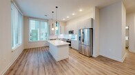 Located at 222 N West St in the heart of downtown Raleigh, NC, this modern 2-bedroom, 1-bathroom unit offers a well-designed single-floor layout with clean, contemporary finishes throughout. Light wood-look flooring runs consistently across every room, lending a cohesive and airy feel to the entire space.

The kitchen serves as a central highlight, featuring sleek gray cabinetry extending to the ceiling, white quartz countertops, a subway tile backsplash, and a full suite of stainless steel appliances including a range, built-in microwave, dishwasher, and French door refrigerator. A white kitchen island with additional cabinet storage anchors the space, complemented by stylish globe pendant lighting. Large windows allow abundant natural light and offer views of the surrounding cityscape.

The spacious primary bedroom provides generous room and is fitted with a ceiling fan, while the second bedroom also benefits from natural light through large windows with city views. A dedicated closet offers organized storage. The bathroom is finished with crisp white subway tile surrounding the tub-shower combo, a white vanity with undermount sink, and matching wood-look flooring. The overall aesthetic is modern and minimal, ideal for urban living in downtown Raleigh.