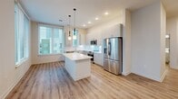 Located at 222 N West St in the heart of downtown Raleigh, NC, this modern 2-bedroom, 1-bathroom unit offers a well-designed single-floor layout with clean, contemporary finishes throughout. Light wood-look flooring runs consistently across every room, lending a cohesive and airy feel to the entire space.

The kitchen serves as a central highlight, featuring sleek gray cabinetry extending to the ceiling, white quartz countertops, a subway tile backsplash, and a full suite of stainless steel appliances including a range, built-in microwave, dishwasher, and French door refrigerator. A white kitchen island with additional cabinet storage anchors the space, complemented by stylish globe pendant lighting. Large windows allow abundant natural light and offer views of the surrounding cityscape.

The spacious primary bedroom provides generous room and is fitted with a ceiling fan, while the second bedroom also benefits from natural light through large windows with city views. A dedicated closet offers organized storage. The bathroom is finished with crisp white subway tile surrounding the tub-shower combo, a white vanity with undermount sink, and matching wood-look flooring. The overall aesthetic is modern and minimal, ideal for urban living in downtown Raleigh.