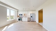 Located at 183–199 E First St in Elmhurst, IL, this thoughtfully designed one-bedroom, one-bathroom unit offers a clean, contemporary aesthetic throughout its efficiently organized single-floor layout. The open-concept kitchen and living area serves as the heart of the unit, featuring light hardwood-style flooring that extends throughout the common spaces, creating a bright and cohesive feel. The kitchen is well-appointed with white shaker cabinetry extending to the ceiling, a glossy subway tile backsplash, light quartz countertops, and a full suite of stainless steel appliances including a gas range, over-the-range microwave, dishwasher, and French door refrigerator. Large windows in the living area flood the space with natural light while providing open views of the surrounding Elmhurst streetscape. A clean, recessed-lit hallway connects the main living area to the private bedroom and bathroom. The bedroom features plush carpeting and additional windows that bring in generous daylight. The bathroom includes a full soaking tub with a tiled surround in crisp white. A dedicated closet provides practical storage, completing this well-planned, modern unit.