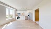 Located at 183–199 E First St in Elmhurst, IL, this thoughtfully designed one-bedroom, one-bathroom unit offers a clean, contemporary aesthetic throughout its efficiently organized single-floor layout. The open-concept kitchen and living area serves as the heart of the unit, featuring light hardwood-style flooring that extends throughout the common spaces, creating a bright and cohesive feel. The kitchen is well-appointed with white shaker cabinetry extending to the ceiling, a glossy subway tile backsplash, light quartz countertops, and a full suite of stainless steel appliances including a gas range, over-the-range microwave, dishwasher, and French door refrigerator. Large windows in the living area flood the space with natural light while providing open views of the surrounding Elmhurst streetscape. A clean, recessed-lit hallway connects the main living area to the private bedroom and bathroom. The bedroom features plush carpeting and additional windows that bring in generous daylight. The bathroom includes a full soaking tub with a tiled surround in crisp white. A dedicated closet provides practical storage, completing this well-planned, modern unit.