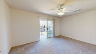 This well-organized one-bedroom, one-bathroom unit is laid out across a single floor, making efficient use of its compact footprint. The living area is finished with neutral-toned carpet and features a ceiling fan with integrated lighting, creating a comfortable and airy atmosphere. A sliding glass door opens onto a private balcony with a railed enclosure, allowing natural light to fill the room while offering views of the surrounding neighborhood.

The bedroom is a generously sized, carpeted retreat with its own ceiling fan and a large window that brings in abundant natural light and additional outdoor views. The room's clean, neutral walls provide a versatile backdrop for any furnishing arrangement.

The galley-style kitchen is a functional space lined with warm wood-toned cabinetry on both sides, complemented by light countertops and hardwood-style flooring. It is equipped with a white refrigerator, stove, and a double-basin sink, offering all essential cooking amenities in a streamlined layout.

The bathroom features hardwood-style flooring consistent with the kitchen, a full tub-and-shower combo with white tile surround, a wood-toned vanity with a light countertop, and a mirror. The overall design of the unit maintains a clean, neutral palette throughout, lending the space a bright and move-in-ready character.