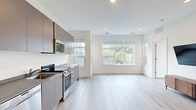 This modern 2-bedroom, 2-bathroom unit on the third floor at 1324 N Capitol St NW offers a clean, contemporary design throughout. Light-toned hardwood flooring runs continuously across the open-plan living and kitchen area, creating a cohesive and airy feel. Large windows flood the living room with natural light and offer treetop views, while recessed lighting adds warmth in the evenings.

The kitchen features sleek, flat-front cabinetry in a sophisticated taupe-gray finish, complemented by matching countertops and a full suite of stainless steel appliances, including a range, over-the-range microwave, dishwasher, and refrigerator. A window above the counter brings in additional daylight.

Both bedrooms are bright and well-proportioned, each outfitted with mirrored sliding closet doors and large windows that frame outdoor views of the surrounding neighborhood. The primary bedroom offers a comfortable footprint with direct access to a bathroom.

The two bathrooms are finished with striking large-format marble-style tile surrounding the soaking tub and shower combinations, paired with crisp white fixtures and brushed nickel hardware, creating a clean, spa-like atmosphere.

The unit's minimalist white walls and modern finishes throughout give it a fresh, move-in-ready appeal in the heart of Washington, DC.