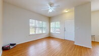 This single-floor home offers a cohesive, light-filled layout defined by warm hardwood-style flooring that extends throughout every room. The entry opens into a spacious living area featuring a ceiling fan and multiple large windows dressed with white horizontal blinds, allowing generous natural light while offering views of surrounding greenery. The open layout flows into additional rooms that share the same bright, neutral palette and wood flooring, creating a consistent and inviting ambiance.

The kitchen is well-equipped and functional, featuring warm-toned wooden cabinetry, granite-look countertops, and a full suite of stainless steel appliances including a gas range, over-the-range microwave, dishwasher, and refrigerator. A peninsula with a stainless steel sink adds both workspace and a casual gathering point.

The home includes two bathrooms: one with a tub and shower combination, and a second featuring a glass-enclosed walk-in shower, both with wood-tone vanity cabinetry and hardwood-style flooring. Each bedroom benefits from large windows overlooking the outdoor surroundings, offering peaceful neighborhood views and ample natural light. The neutral tones, clean finishes, and consistent flooring throughout give the home a cohesive and move-in-ready feel.