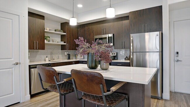 Gran isla de cocina con asientos e iluminación colgante moderna. - Parkway Lofts