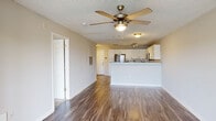Located at 100 Patriot's Pointe Dr in Hillsborough, NC, this single-floor residence offers a well-designed, open-concept layout that seamlessly connects the main living areas. The living room features durable wood-style flooring, neutral wall tones, and a ceiling fan with integrated lighting, creating a comfortable and functional space. A large window in an adjoining sitting or dining area allows natural light to fill the interior, offering views of the surrounding neighborhood.

The kitchen is a standout feature, equipped with stainless steel appliances including a refrigerator, range, and microwave. White shaker-style cabinetry with brushed nickel hardware lines the walls, complemented by granite countertops and a classic subway tile backsplash. A peninsula counter provides additional workspace and casual dining potential, with track lighting overhead enhancing visibility.

The bedrooms are carpeted for comfort, each outfitted with ceiling fans and windows that invite natural light. The bathroom includes a white vanity with ample storage, a mirrored medicine cabinet, and wood-style flooring that ties back to the main living areas. Throughout the residence, a cohesive neutral palette and consistent finishes contribute to a clean, move-in-ready aesthetic.