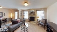 This single-floor residence offers a thoughtfully designed layout that balances comfort and functionality across several well-defined living spaces. The living room serves as the centerpiece of the home, featuring a classic fireplace with a decorative mantle, plush carpeting, and multiple windows that allow generous natural light to fill the room. An adjoining entry area provides a welcoming transition into the space. The open-concept flow connects the living room to a dedicated dining area, which features two-tone wall accents and warm overhead lighting, ideal for intimate meals. The kitchen is efficiently arranged with warm wood cabinetry, granite-style countertops, a full suite of white appliances, and ample storage — all connecting seamlessly to the dining and living areas via a breakfast bar. The bedrooms are carpeted and serene, with the primary bedroom offering natural light through dual windows and generous wall space. A full bathroom features wood cabinetry, a single-sink vanity, tile flooring, and a shower-tub combination. A dedicated utility area with washer/dryer hookups and an electrical panel adds everyday convenience. Throughout the home, neutral tones and consistent finishes create a cohesive, comfortable ambiance.