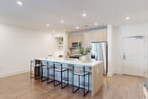 Located in Atlanta's vibrant 30307 zip code, this thoughtfully designed one-bedroom, one-bathroom residence offers a seamless blend of modern aesthetics and functional living. The open-concept layout connects the living room, dining area, and kitchen into one cohesive, light-filled space. Warm hardwood-style flooring flows throughout, complemented by crisp white walls and recessed lighting that enhances the bright, airy ambiance. Large windows invite generous natural light into the living area, which also features a ceiling fan and sliding glass door access.

The kitchen is a standout, anchored by an oversized waterfall-edge island with seating for four, ideal for casual dining and entertaining. Light wood cabinetry, stainless steel appliances including a refrigerator, range, and microwave, a tile backsplash, and open display shelving complete the contemporary culinary space.

The bedroom is a serene retreat with hardwood-style flooring, a ceiling fan, and a window for natural light. Two closets provide ample storage throughout the home. The bathroom is elegantly finished with marble-look tile, a glass-enclosed walk-in shower, a soaking tub, a floating wood vanity, and a framed mirror. A dedicated laundry area and additional closet space round out this efficiently designed residence.
