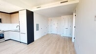 Located in East Harlem at 205 E 110th Street, this thoughtfully designed two-bedroom, one-bathroom residence offers a clean, contemporary aesthetic throughout its single floor. Light-toned hardwood flooring runs consistently through every room, creating a cohesive and airy feel.

The kitchen is a standout feature, combining white lower cabinetry with warm wood upper cabinets and a dark accent panel backsplash. Stainless steel appliances, including a full-size range, are complemented by floor-to-ceiling black-framed windows that flood the space with natural light and offer open views of the surrounding East Harlem skyline.

The primary bedroom is generously proportioned, benefiting from a large black-framed window with city views, while the second bedroom features louvered closet doors and its own access to additional storage. Both rooms are finished in crisp white walls, enhancing the sense of brightness and space.

The bathroom is elegantly appointed with full-height marble-effect wall tiling, a soaking tub with a matte black shower fixture, a floating walnut vanity, and large-format light tile flooring — a refined contrast to the minimalist design found throughout the rest of the residence.

Black hardware details on doors and fixtures provide a consistent modern accent across the home, tying together the overall design language with precision and style.