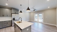 Located at 437 Roanoke Rd in Daleville, Virginia, this well-appointed single-floor residence offers a thoughtfully designed layout across a comfortable footprint. The open-concept living, dining, and kitchen area serves as the heart of the home, featuring light-toned luxury vinyl plank flooring, crown molding, recessed lighting, and a ceiling fan. The kitchen is outfitted with gray shaker-style cabinetry, white quartz countertops, a center island with an undermount sink and pendant lighting, and a full suite of stainless steel appliances including a refrigerator with ice maker, electric range, microwave, and dishwasher. French doors lead to a private balcony, filling the living area with natural light. The generously sized primary bedroom is carpeted and includes a ceiling fan. The bathroom features a gray shaker vanity with white countertop, a combination tub and shower, and wood-look flooring. A second room serves as a dedicated office or flex space with carpet flooring. An in-unit laundry room houses a stacked Whirlpool washer and dryer. Two closets provide ample storage throughout. The space is finished in neutral tones throughout, creating a clean, modern aesthetic.