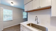 This single-floor residence offers a thoughtfully designed layout with modern finishes throughout. The galley-style kitchen is a standout feature, showcasing crisp white shaker cabinetry, gleaming quartz countertops, and a classic white subway tile backsplash. Stainless steel appliances — including a refrigerator, dishwasher, and range — complement the undermount stainless sink fitted with a pull-down faucet. Durable wood-look flooring runs through the kitchen and main living areas, adding warmth and visual continuity. Natural light filters in through multiple windows dressed with blinds, brightening each room with a clean, airy feel. The living and main rooms are generously proportioned, offering open, flexible spaces with neutral wall tones. The bedrooms are finished with soft carpeting, ceiling fans with light fixtures, and well-organized reach-in closets providing ample storage. The bathroom is finished in clean white tiling and features a full soaking tub and shower combination. The overall design palette of soft grays, warm whites, and natural wood tones creates a cohesive and inviting atmosphere throughout this move-in ready residence.
