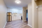 This thoughtfully updated one-bedroom, one-bathroom apartment in Richmond, BC offers a well-designed layout across a single floor. Light-toned laminate hardwood flooring flows throughout, lending a clean and cohesive feel to every room. The living room is a bright, open space warmed by a baseboard heating system and features sliding glass doors that open directly onto a private patio — a charming outdoor retreat overlooking a landscaped green lawn and mature trees. A standout design detail is the set of double sliding barn doors with black matte hardware, elegantly separating spaces while adding a contemporary farmhouse character. The kitchen is efficiently laid out with crisp white shaker cabinetry, a marble-style backsplash, stainless steel appliances including a refrigerator and range, and a stainless sink — all finished to a modern standard. The bedroom is a comfortable, well-proportioned room with a window framing views of the surrounding greenery and building exterior. The bathroom features a full tub-shower combination with marble-look surround panels, a white vanity with quartz-style countertop, and light flooring that ties the space together. Two closets and a hallway complete the practical layout of this well-appointed home.