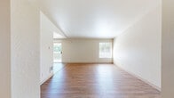 This single-floor, 3-bedroom, 2-bathroom residence in Port Orchard, Washington offers a practical and comfortable layout. The open living and dining area is a highlight of the home, featuring warm wood-style flooring, vaulted ceilings, and an abundance of natural light through multiple windows and a sliding glass door that opens to an outdoor deck with views of the surrounding greenery.

The kitchen is efficiently designed with warm wood cabinetry, a double-basin sink, ample counter space, and black appliances including a range and refrigerator, all set on light wood-style flooring. Adjacent dining and living areas flow seamlessly, making the space well-suited for everyday living.

The three bedrooms are carpeted and well-proportioned, each featuring windows that bring in natural light. The primary bedroom offers a comfortable retreat with closet storage. The secondary bedrooms are versatile spaces, one featuring sliding wood-panel closet doors.

Both bathrooms are functional and clean in design. One features a single-sink vanity with light wood cabinetry, a large mirror with overhead lighting, and tile flooring. The second bathroom includes a full tub-shower combination with clean white surrounds. A hallway connects the bedrooms and living spaces, completing this well-organized floor plan.