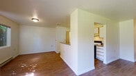 Located at 2727 East 53rd Avenue in Spokane, Washington, this single-floor unit offers a practical and comfortable layout suited for everyday living. The open living area is finished with warm hardwood-style flooring that extends throughout the main living spaces, and a sliding glass door floods the room with natural light while providing direct access to a green outdoor area. Baseboard heating is present throughout, ensuring year-round comfort.

The kitchen is efficiently designed with white cabinetry, a full-size refrigerator, an electric range, and laminate countertops. A peninsula-style pass-through connects the kitchen to the living area, creating an open and communicative flow between the two spaces.

The bedrooms are carpeted for added comfort and each features closet storage. The layout, as seen in the dollhouse view, includes a well-defined hallway connecting the bedrooms to the rest of the unit, offering a clear separation between living and sleeping areas.

The full bathroom is equipped with a single-sink vanity with a laminate countertop, a combination tub and shower, and hardwood-style flooring. Clean white walls and simple chrome fixtures maintain a consistent, understated aesthetic throughout the unit. Overall, the space presents a straightforward, functional design with a bright and neutral palette.