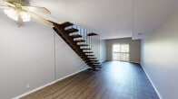 Located at 2350 Timberview Rd in Kirkwood, Missouri, this two-story property offers a well-designed layout with notable architectural details throughout. The main level features an open living area finished with warm, wood-toned luxury vinyl plank flooring and neutral gray walls that create a clean, modern backdrop. A standout feature of the main level is the dramatic open-tread staircase, constructed with rich dark wood treads suspended by slender black metal rods, lending a contemporary, almost sculptural quality to the space. A ceiling fan is also present, adding functional comfort. Sliding glass doors on the main level open to an outdoor balcony, allowing natural light to filter in and providing views of the surrounding greenery.

The upper level showcases a spacious room distinguished by soaring vaulted ceilings with exposed dark wood beams and a tongue-and-groove wood ceiling, adding warmth and architectural character. A sliding glass door leads to an additional outdoor balcony, reinforcing the connection to the natural setting. A bathroom is also present, featuring tile flooring, a vanity with a gray countertop, under-sink cabinetry, and a wall mirror. The overall ambiance across both floors is modern yet inviting, with consistent flooring and neutral tones throughout.