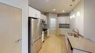 This single-floor residence offers a clean, modern design with a thoughtful layout visible in its open floor plan. The living areas feature light hardwood-style flooring that runs throughout the main spaces, complemented by neutral wall tones that create a bright and welcoming ambiance. Recessed lighting and vertical blinds over a sliding door enhance the main living area, which connects seamlessly to the rest of the home.

The kitchen is well-equipped with white shaker-style cabinetry, stainless steel appliances including a refrigerator, range, and built-in microwave, and granite-style countertops. Pendant lighting and recessed fixtures illuminate the space, while a double sink and additional cabinetry provide ample storage and functionality. A frosted-glass pantry door adds a subtle design detail.

The bedrooms feature plush carpeting and windows that allow natural light to filter in, offering a comfortable and quiet retreat. One bedroom includes direct access to a bathroom and closet area, showcasing a practical layout.

The bathrooms are finished with granite-style vanity countertops, white cabinetry, and brushed nickel fixtures. One bathroom features a tub-shower combination with a curved curtain rod, while another includes a well-lit vanity mirror with modern light fixtures. Overall, the space presents a clean, functional, and contemporary living environment.