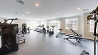 Located at 633 Springfield Ave in Berkeley Heights, NJ, this fitness center offers a generously sized, single-floor space designed to accommodate a comprehensive range of workout activities. The facility is thoughtfully laid out to maximize usable floor area while maintaining an open, uncluttered feel throughout.

The interior features neutral-toned walls, crown molding, and recessed lighting that collectively create a clean, polished atmosphere. Dark rubber flooring spans the entire space, providing durability and safety underfoot. Large arched windows along multiple walls invite substantial natural light, contributing to an energizing and welcoming environment with views of the surrounding exterior.

The cardio zone is well-stocked with treadmills, ellipticals, stationary bikes, and a rowing machine, all arranged to face the windows. The strength training area includes multiple cable and resistance machines, a multi-station cable system, a dumbbell rack with a full set of free weights, and adjustable benches. Floor-to-ceiling mirrors along one wall visually expand the space and assist exercisers with form. A wall-mounted television provides entertainment options. An open stretch area offers additional flexibility for floor exercises or functional training, completing this fully equipped, amenity-rich fitness facility.
