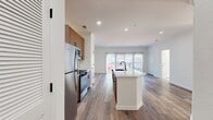 This contemporary 910 square foot apartment offers a harmonious blend of style and functionality. The open-concept layout seamlessly integrates the kitchen and living areas, creating an inviting space for both relaxation and entertaining. The kitchen boasts modern wood-grain cabinetry, stainless steel appliances, and a pristine white countertop with a spacious island.

The two bedrooms are generously sized, with the primary bedroom measuring 160 square feet. Large windows in both rooms flood the spaces with natural light, while plush carpeting adds warmth and comfort. Each bedroom has access to its own bathroom, featuring sleek fixtures, wood-tone vanities, and a combination of tiled and wood-look flooring.

Throughout the apartment, you'll find a cohesive design aesthetic with crisp white walls, recessed lighting, and a mix of carpeted and wood-look flooring. The living area extends to a balcony or patio, offering additional outdoor space. Ample closet space in both bedrooms and hallways provides excellent storage options.

This single-story unit combines modern amenities with a thoughtful layout, creating an ideal living space for those seeking contemporary comfort and style.
