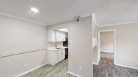 Located at 9750 Forest Ln in Dallas, TX, this single-story, one-bedroom, one-bathroom unit offers a clean, modern aesthetic with thoughtful updates throughout. Wood-look plank flooring flows seamlessly across the living, dining, and bedroom areas, lending a cohesive and contemporary feel. Neutral warm-beige walls and white trim complement the light palette, creating a bright and welcoming atmosphere.

The galley-style kitchen is well-appointed with crisp white cabinetry, brushed nickel hardware, a white quartz countertop, a stainless steel undermount sink, and black appliances including a refrigerator and electric range. A textured ceiling with recessed lighting adds character overhead.

The open living and dining area benefits from natural light through a window with blinds and features a ceiling fan with a light fixture, keeping the space comfortable year-round. Crown molding accents the living area, adding a refined touch.

The bedroom is a comfortable, private retreat with its own ceiling fan, a window for natural light, and continued wood-look flooring. A dedicated closet provides convenient storage.

The bathroom is clean and functional, featuring a tub/shower combination with tiled surround, a toilet, and matching wood-look flooring. The unit's efficient, single-floor layout ensures easy navigation throughout the space.